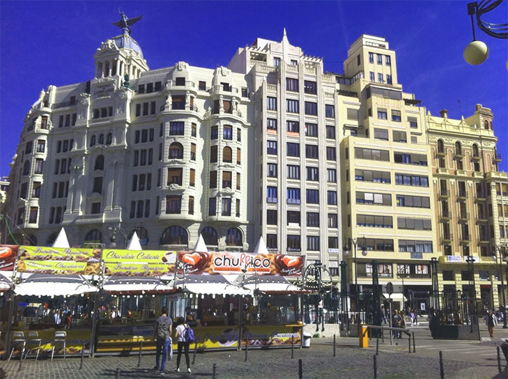 the biggest lie expats tell themselves. Image of Valencia with churro stands in front of apartment blocks.