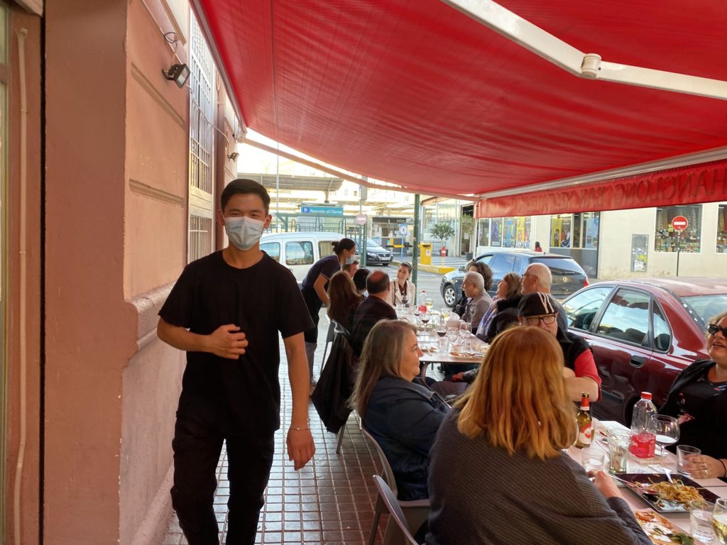 20 reasons not to visit valencia spain. outdoor chinese restaurant with people sitted and a man in black tshirt to the side.