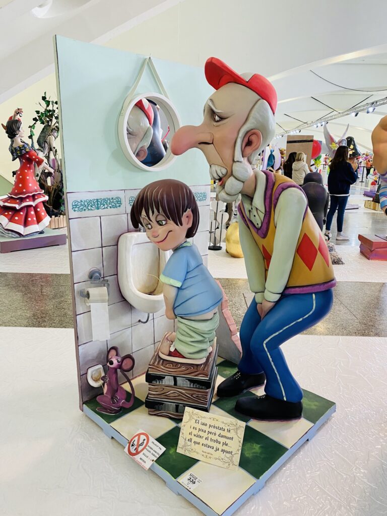 man dying to pee with a small boy already using the urinal in Fallas in Valencia post.